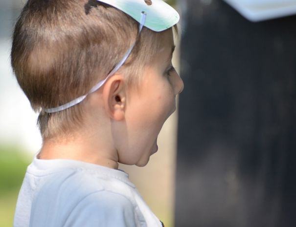 Et barn med en maske skubbet op i panden, der står og råber.