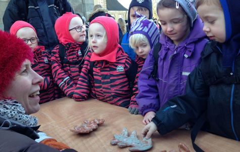 En gruppe børn står omkring et bord og kigger på keramikgenstande, der er formet som blade.
