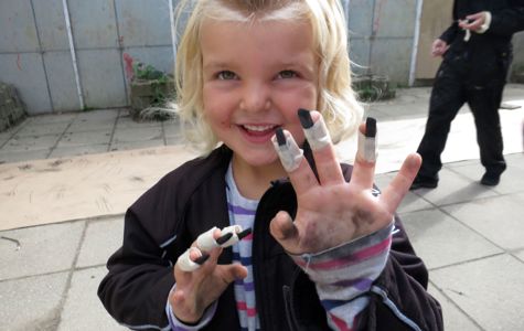 Barn viser sine hænder frem, hvor der er tapet kul-stykker fast til fingrene